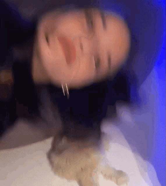 a blurry picture of a woman laying on a bed with a blue light in the background .