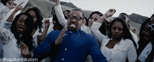a man in a blue shirt is surrounded by a crowd of people dancing ..