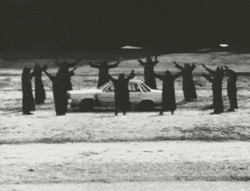a group of people are standing around a car with their arms in the air .