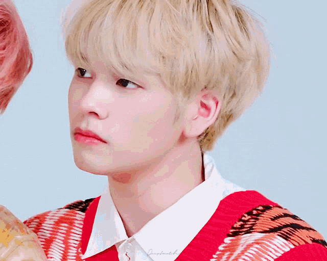 a close up of a person 's face with a red and orange sweater
