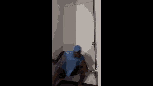 a person in a blue shirt is standing in front of a door .