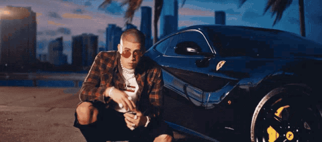 a man wearing sunglasses sits next to a car that says supreme on it