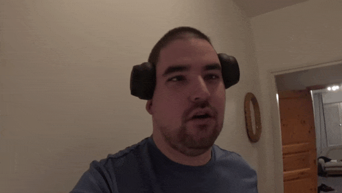 a man wearing headphones and a blue shirt has the number 0 on the wall