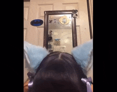 a person wearing a cat ear headband looks at themselves in a mirror