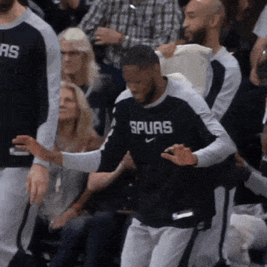 a man wearing a shirt that says spurs is being helped by another man