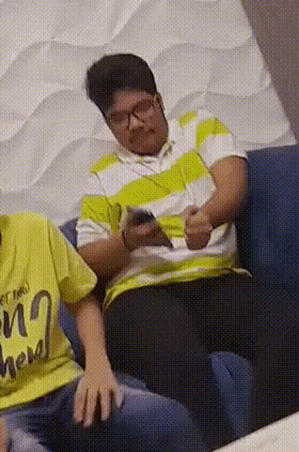a man wearing glasses is sitting on a blue couch with a yellow shirt that says ' i love you ' on it