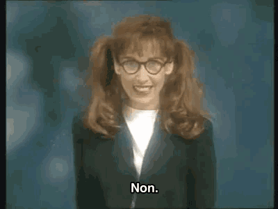 a woman with red hair and glasses is wearing a suit and smiling while saying non .