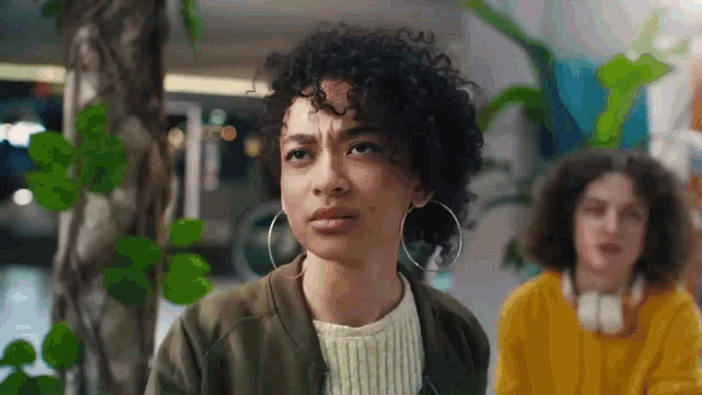 a woman with curly hair and hoop earrings is standing next to a man in a yellow shirt .