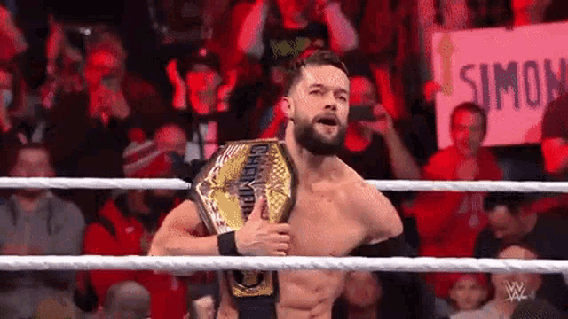 a wrestler is holding a wrestling championship belt in a ring .