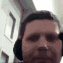a man with a beard and headphones is taking a selfie .