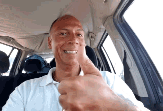 a man giving a thumbs up in a car