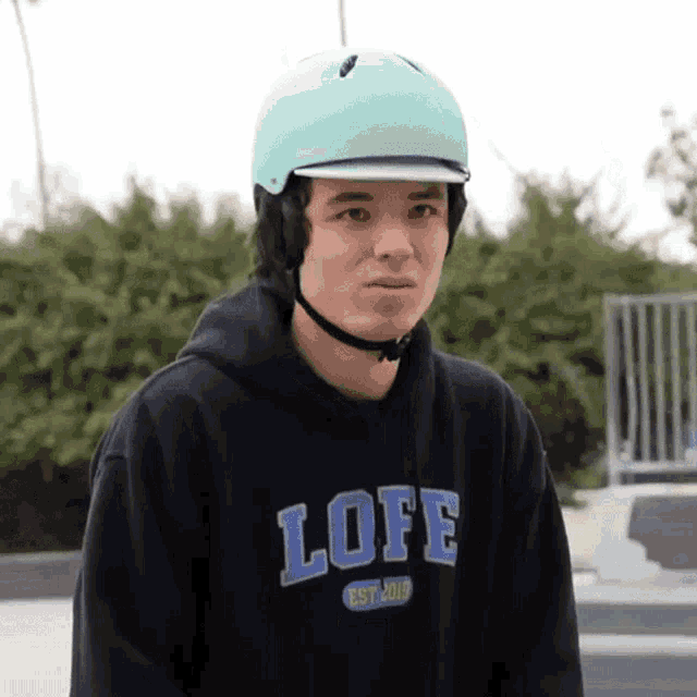a young man wearing a blue helmet and a black lofe sweatshirt