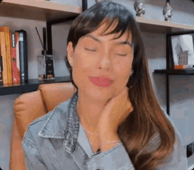 a woman is sitting in a chair with her eyes closed and her hands on her face .