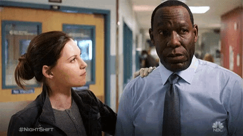 a man and a woman are standing next to each other in a hallway and the man has a nbc logo on his shirt