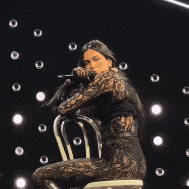 a woman in a black lace outfit sits on a chair