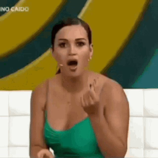 a woman in a green dress is giving the middle finger .