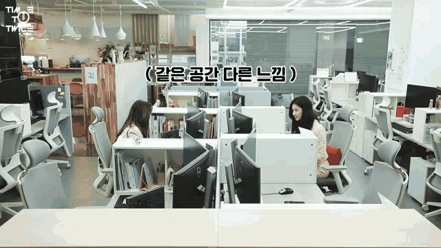 a woman sits at a desk in an office with a dell monitor
