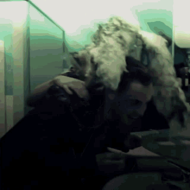 a man in a black shirt is washing his face in a bathroom
