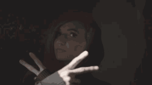 a woman with red hair and a black hoodie is making a peace sign