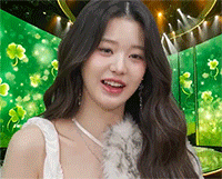 a woman in a white dress is standing in front of a green background with clovers on it .