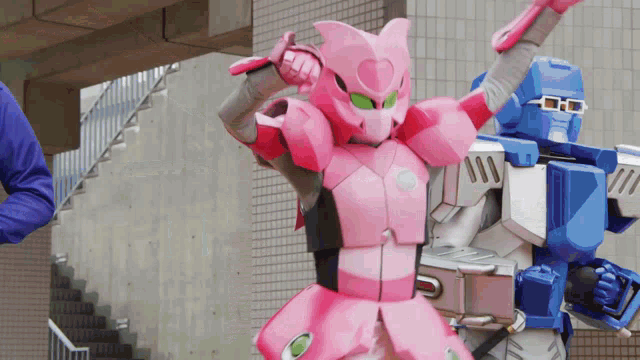 a pink robot and a blue robot are standing next to each other in front of stairs