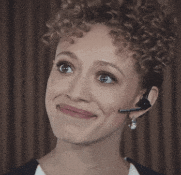 a woman with curly hair wearing a headset making a funny face