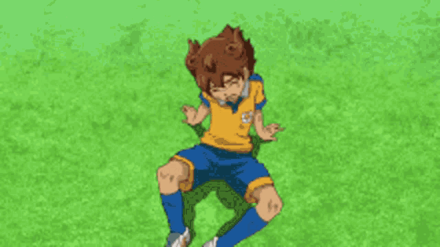 a boy in a yellow shirt and blue shorts is laying on the grass with his hands reaching for him