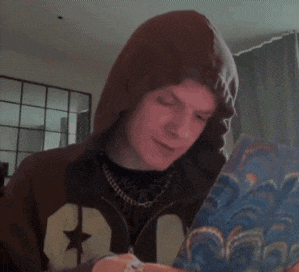 a young man wearing a brown hoodie with a star on it