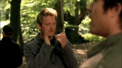 two men are standing in the woods talking to each other