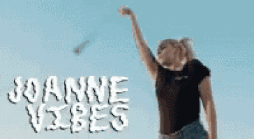 a woman is standing on a beach with her arms in the air and the words joanne vibes on the bottom .