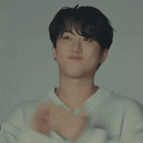 a close up of a man wearing a white sweater and earrings