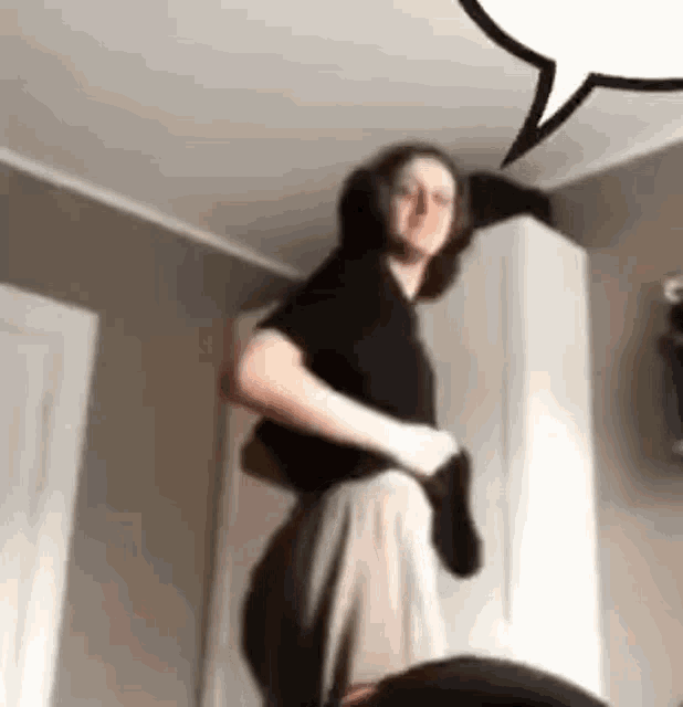 a man is standing in a room with a speech bubble in the background .