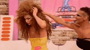a man is holding a woman 's hair while a woman in a yellow dress looks on .