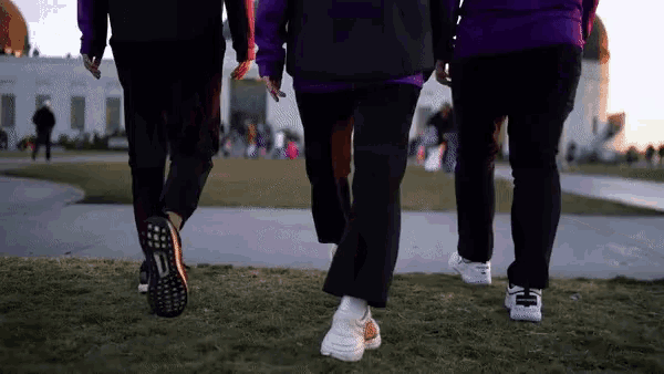 a group of people are walking down a sidewalk and one of their shoes says adidas on it