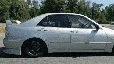 a silver car with a black wheel is parked on the side of the road