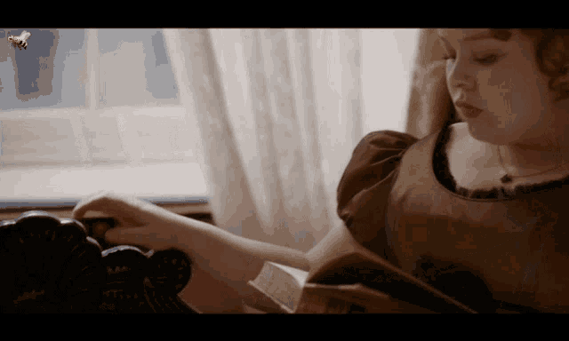a bee is flying over a woman 's head while she reads a book
