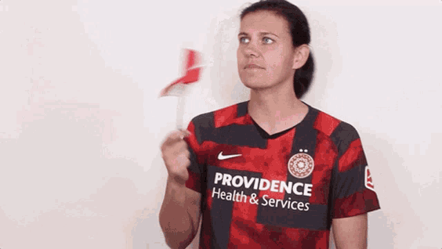 a woman wearing a providence health & services shirt holds a small canadian flag