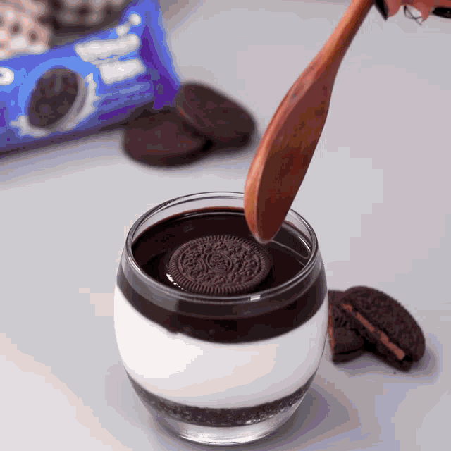 a wooden spoon is dipping an oreo cookie into a glass