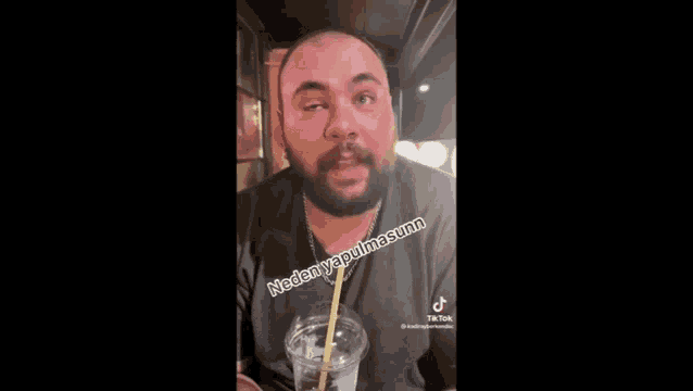 a man with a beard is drinking a drink with a straw and making a funny face .