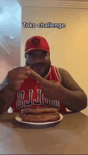 a man wearing a chicago bulls jersey is eating a plate of hot dogs .