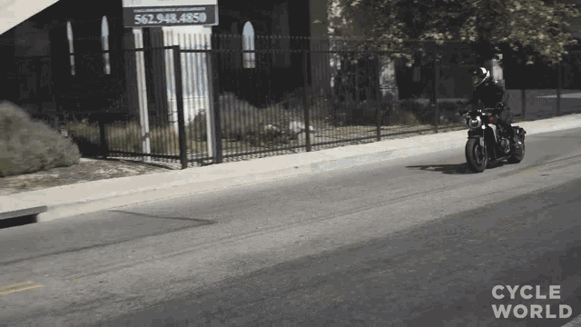 a person riding a motorcycle down a street with the words cycle world written on the bottom