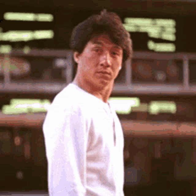 a man wearing a white shirt is standing in front of a building .