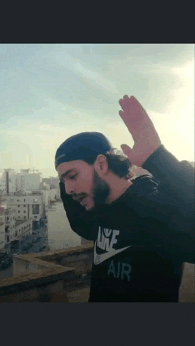 a man wearing a black nike air sweatshirt and a blue hat