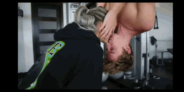 a woman is holding a man 's neck in a gym .