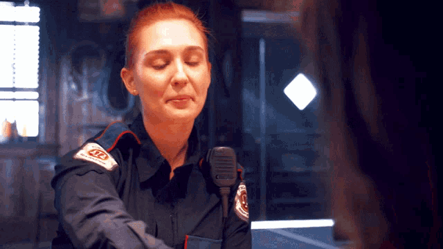 a woman talking into a microphone with a badge that says tp on it