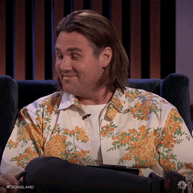 a man wearing a floral shirt is sitting in a chair on nbc songland