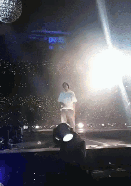 a man in a white shirt is standing on a stage in front of a disco ball