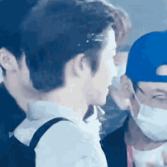 a man wearing a mask is talking to another man in a blue hat .