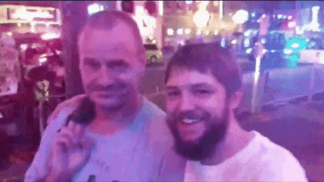 a man with a beard is standing next to another man with a microphone .