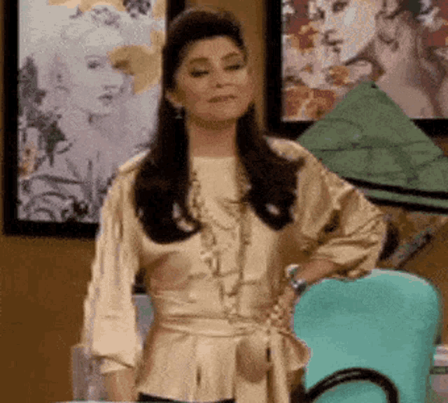 a woman in a gold top is standing in front of a green chair .